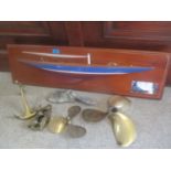 A model boat on a wall hanging plaque with an inscribed plaque and other boat related items