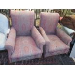 A pair of Edwardian upholstered armchairs on short cabriole front legs and ceramic castors