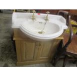 A ceramic sink raised on a light oak base having two cupboard doors, 39" h x 29 1/4"w