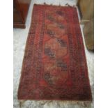 A Middle Eastern hand knotted Afghanistan red ground rug with tasselled ends 85 1/2" x 42 1/2"