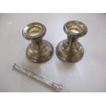 A pair of silver dwarf candlesticks, total weight 192.3g, together with a silver propelling pencil