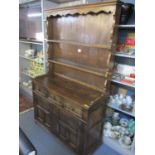 A reproduction oak dresser having a plate rack above three drawers and two cupboard doors, 76 1/2"