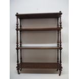 A Victorian walnut what-not with a low upstand, over four shelves and turned baluster columns, on