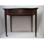 A Jas Shoolbred & Co mahogany serpentine front writing table with a green leather scriber, over a