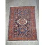 A Persian Kazak rug with three medallions and geometric motifs on a dark blue ground, 75" x 57"