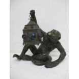 An early 20th century patinated spelter lamp fashioned as a seated monkey, holding a lantern with