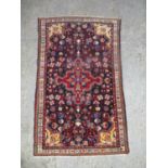 A Persian rug with a central medallion and geometric flowers, on a dark blue ground, 67" x 40"