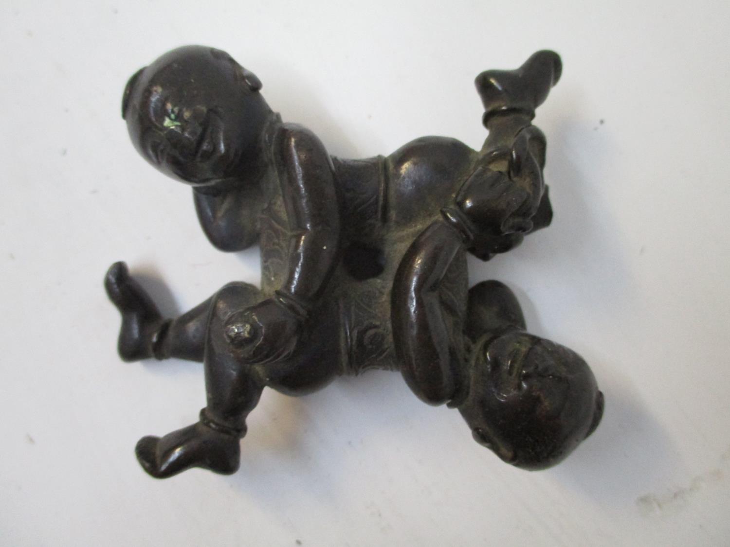 A late 19th century Chinese bronze group of two children head to foot, lying on their sides, 2 1/2"w