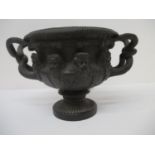 A late 19th century cast bronze urn with twin twig handles, a fruiting vine border, three bearded