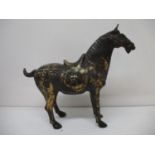A 20th century brown patinated and gilt cast iron model of a Tang horse with a saddle and harness,