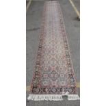 A Persian design runner with repeated geometric flowers and motifs on a pale blue ground, 33" x 197"