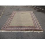 An Indian carpet with repeated boteh on a cream ground within a red, blue and yellow border