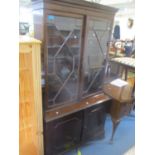 A reproduction mahogany bookcase with dentil moulded cornice, glazed doors, cupboards below on