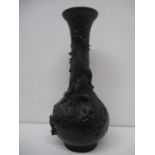 A late 19th century Japanese bronze vase of ovoid form with a tall neck and flared lip, decorated