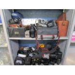 Two shelves of mixed cameras, binoculars, camera lens, accessories and camera bags