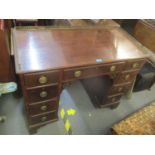 An early 19th century mahogany kneehole desk having a metal gallery top, one long drawer, four short