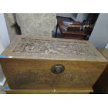 An Asian early to mid 20th century carved camphor wood chest, heavily carved with figure groups