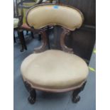 A Victorian mahogany nursing chair having scroll shaped supports and feet
