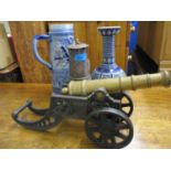 A German stoneware jug and vase, a brass and iron model cannon and a minors lamp