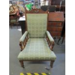 A late Victorian walnut upholstered open armchair on turned front legs and ceramic castors