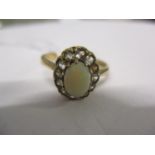 A 9ct gold, opal and diamond ring having a central opal surrounded by eleven small diamonds (one