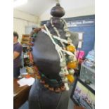 A display mannequin on wooden stand with a selection of beaded necklaces and pendants to include
