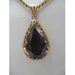 A yellow metal pear shaped pendant with fine rope decoration and inset with a pear shaped amethyst