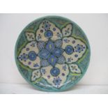 A 19th/20th century Iznic dish decorated with flowers and patterns in green, blue and yellow with