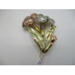 A three tone gold coloured metal brooch fashioned as two flowers, the stamens and stem set with