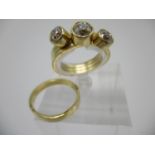 An 18ct gold three piece interlocking ring set, each set with a diamond in a rub-over setting, on