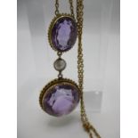 A 9ct gold neck chain with yellow metal pendant with one oval bezel cut amethyst and one round bezel