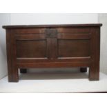 An early 18th century oak chest with a panelled, hinged top, sides and front with an iron catch,