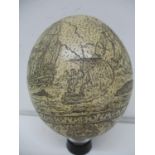 An 18th/19th century Ostrich egg scrimshaw carved with a waling scene, ships and mountains, over a