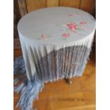 A piano shawl in cornflower blue with pink floral embroidery to one corner having a long blue