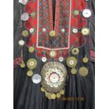 An early 20th century Afghan tribal costume in red and black decorated with mother of pearl,