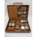 A 1940s gentleman's brown leather travelling vanity case enclosing silver lidded three glass jars, a