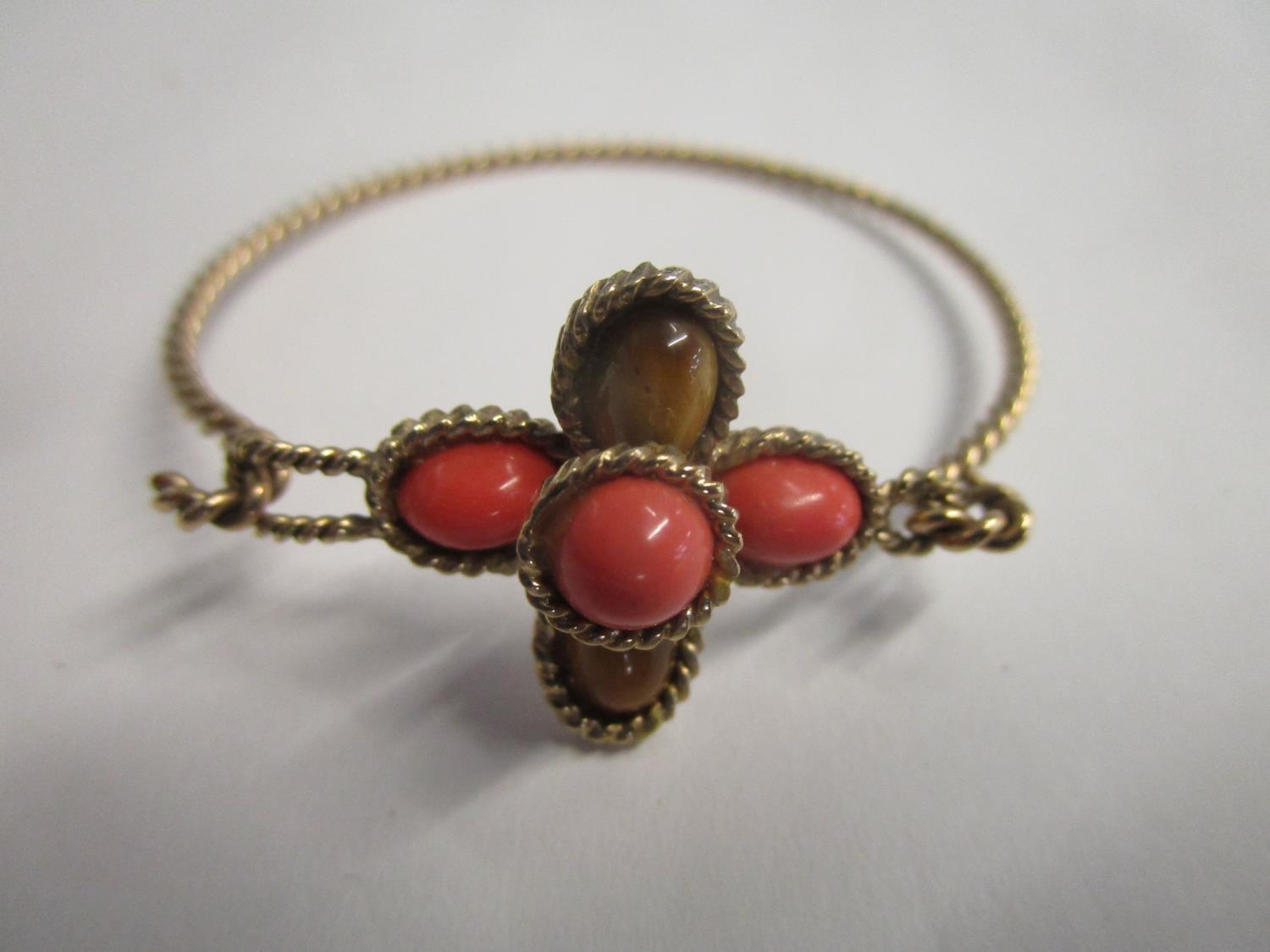 A 9ct yellow gold rope twist bracelet set with tigers eye and coral coloured stones in a cross