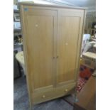 A modern light oak two door wardrobe with a single drawer below 76 3/4" H x 44 1/2" W Location: G