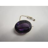 A yellow gold coloured set oval amethyst brooch on safety chain