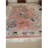 A large Chinese pink ground rug having a cream border and tasselled ends, 144" x 108"