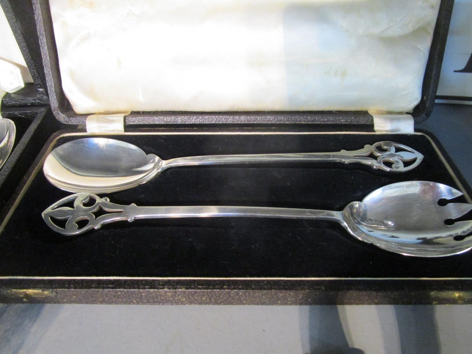 A quantity of silver plated items to include cased servers and a glass and silver topped dressing