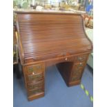 An early 20th century Gillows, tambour roll top, twin pedestal desk having eight drawers flanking