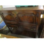 A reproduction oak side cabinet having two cupboard doors above two brush slides, two drawers and
