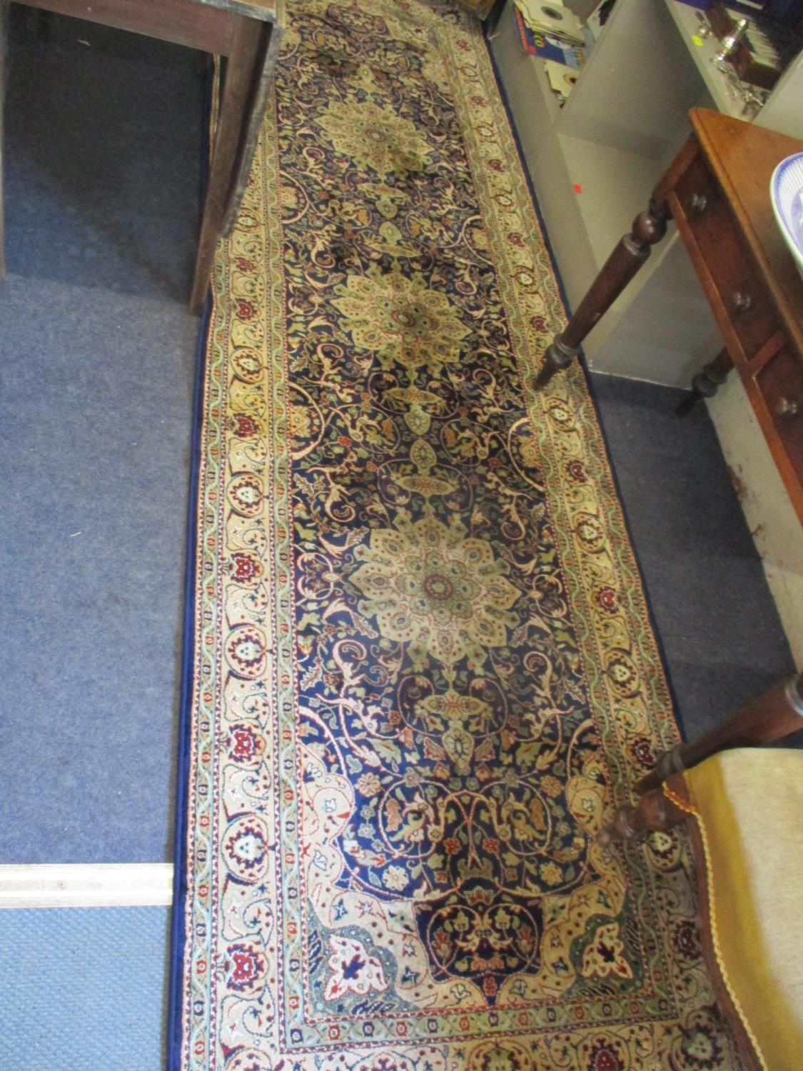 A Middle Eastern machine made woollen carpet having a navy ground with three large central motifs