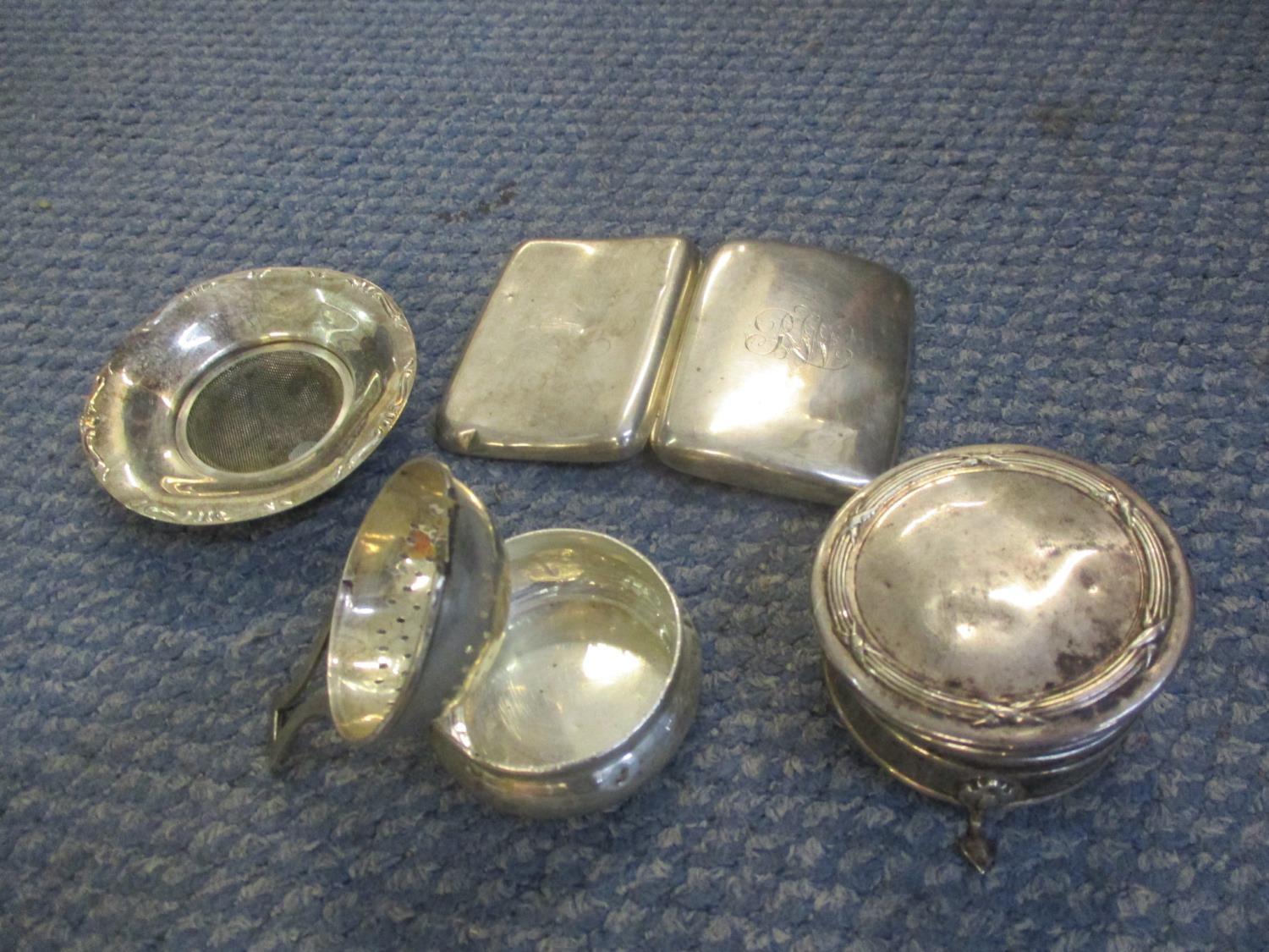 A small collection of silver items comprising a dish, cigarette case, a tea strainer and holder