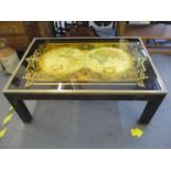 A mahogany painted coffee table with brass hardware having a painted glass top depicting a