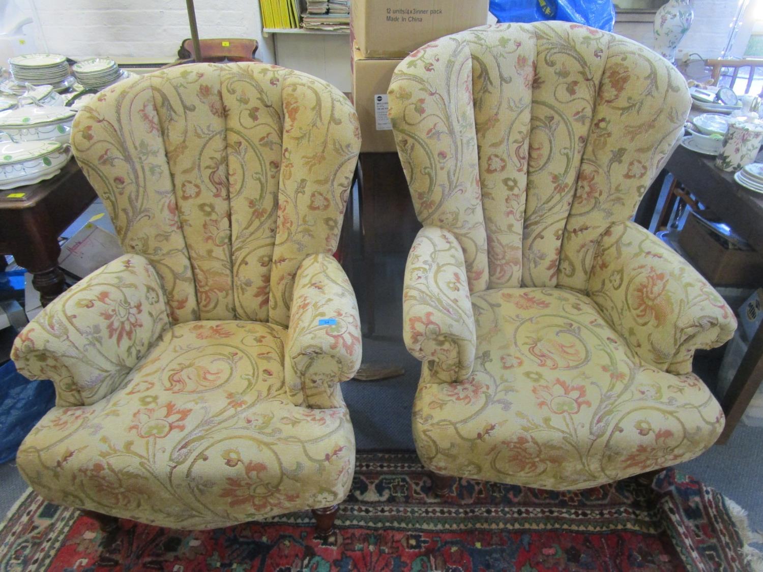 A pair of modern Victorian style wing back armchairs with floral upholstery, on turned legs