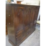 A large reproduction oak side cabinet having four panelled clipboard doors above nine drawers 59 1/