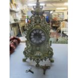 An ornate brass cased mantle clock, the dial with white enamelled and black painted roman