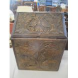 An early 20th century carved oak box with a sloping hinged top